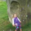 Girl Leaning Against Rock With Bubbles Blowing By