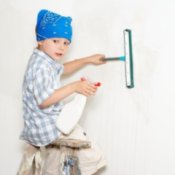 Young boy sitting on a step ladder cleaning a wall.
