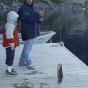 Man and a boy catching a fish on a dock.