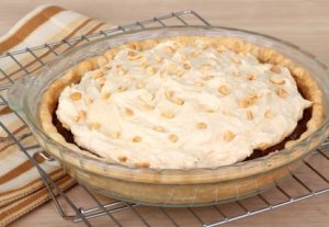A whole uncut peanut butter pie on a cooling rack.