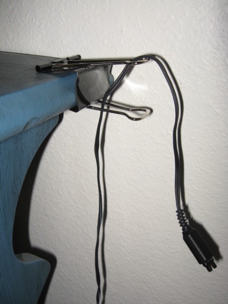 Large paper clip attached to table for cord.