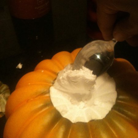 Using a spoon to scoop out interior of Styrofoam pumpkin.