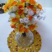 Plarn centerpiece mat with vase of silk flowers.