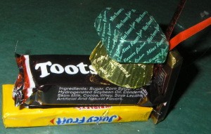 Foil wrapped mint glued on top of Reese's and addition of small candy bar and ribbon hanger.
