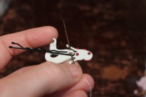 Beginning to sew button on to pin.