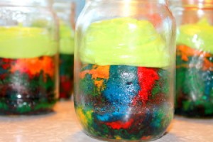 Rainbow cake with frosting, served in the mason jars.