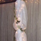 A tulle wedding decoration with greenery and white lights.