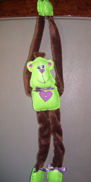 Green and brown monkey hanging by arms.