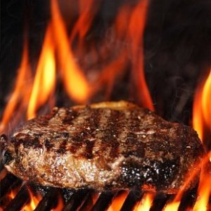 A steak being cooked on a grill.