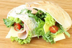 Pita sandwich with lettuce and tomato in it.