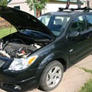 A black car with the engine hood up.