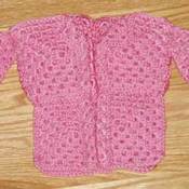 A crocheted doll's sweater in pink.