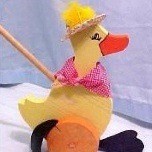 A yellow duck push toy made out of wood.