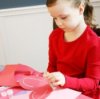 A photo of a girl making paper hearts.