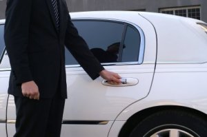 Man opening door of a white limousine.