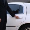 Man opening door of a white limousine.