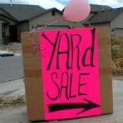 Yard sale sign in a driveway, with pink balloon.