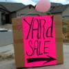 Yard sale sign in a driveway, with pink balloon.
