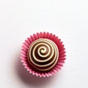 Chocolate truffle with spiral design in pink paper cup.