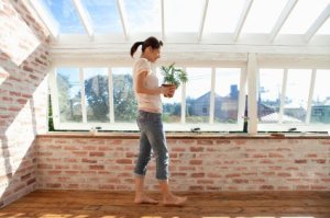A woman stand in a room built using recycled windows.