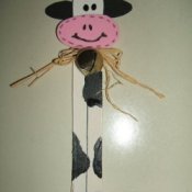 Μια παιχνιδιάρικη σελιδοδείκτη αγελάδα σε μαύρο και λευκό και ροζ με ένα ρουστίκ τόξο ..