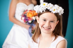 Flower Girl Smiling in Front of Bride and Groom