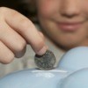 Boy Putting Quarter in Piggy Bank