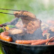 Several types of meats being grilled on a round grill