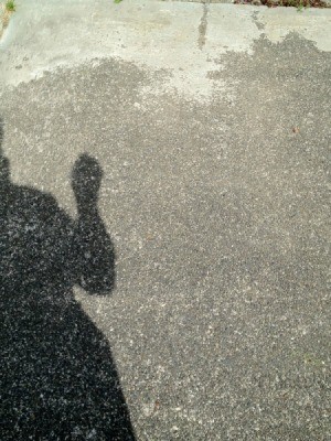 Shadow of man holding pinhole viewer aligned with sun.