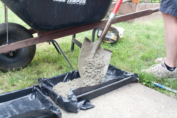 Pouring Concrete into Mold with Shovel
