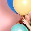 A girl looking through birthday balloons.