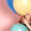 A girl looking through birthday balloons.