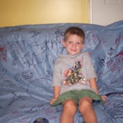 Child sitting on couch covered with keepsake tablecloth.