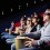 Audience in theater wearing 3D glasses and eating popcorn.