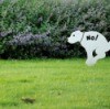 A no dog pooping sign in someone's lawn.