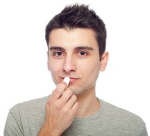 A young man putting on chapstick.