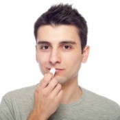 A young man putting on chapstick.