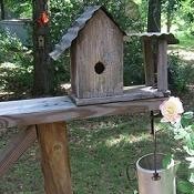 A wooden birdhouse near a rose.