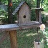 A wooden birdhouse near a rose.