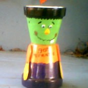 Two clay pots decorated to make a smiling Frankenstein monster candy dish.