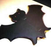 Black bat with wings spread.