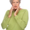 A woman in pain wearing dentures.