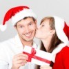 A woman kissing her boyfriend and giving him an envelope with homemade coupons in it.