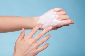 A person rubbing lotion on their hands.