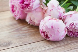 A bunch of fresh peonies on a wood floor.