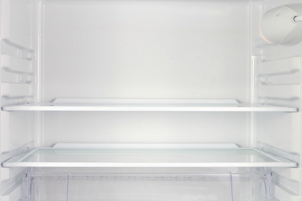 What are the potential causes of water in the bottom of a refrigerator?