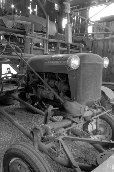 An old tractor in a wooden barn, in black and white