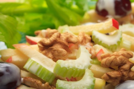 A close up of a salad with celery, grapes and apple