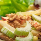 A close up of a salad with celery, grapes and apple