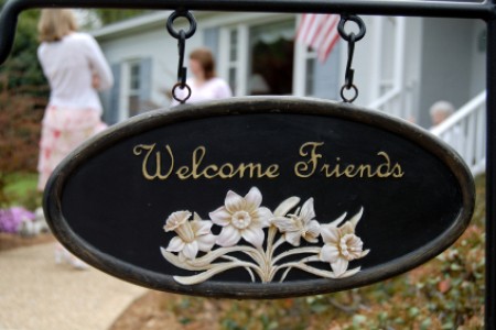 A sign in front of a house welcoming friends to visit.